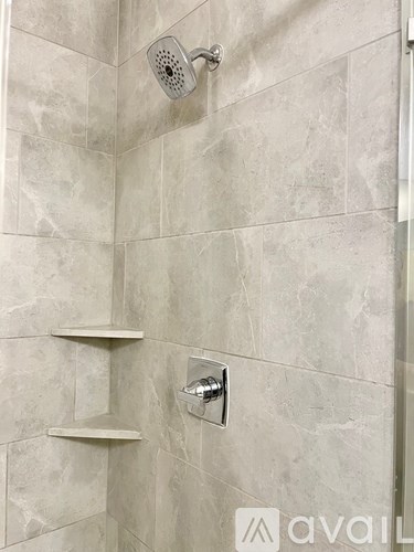 A shower area with a wall-mounted shower head and a handheld shower head.