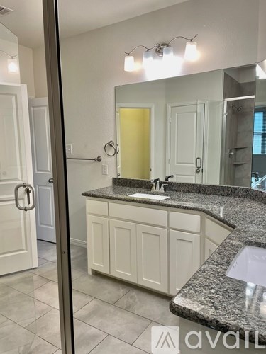 A bathroom with a granite countertop and white cabinets.