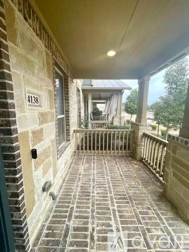 A porch with a brick patterned floor and a stone wall.