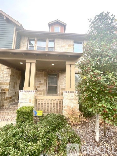 A house with a balcony and a tree in front.