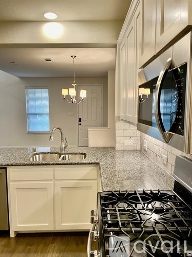 A modern kitchen with white cabinets and a black stove top.