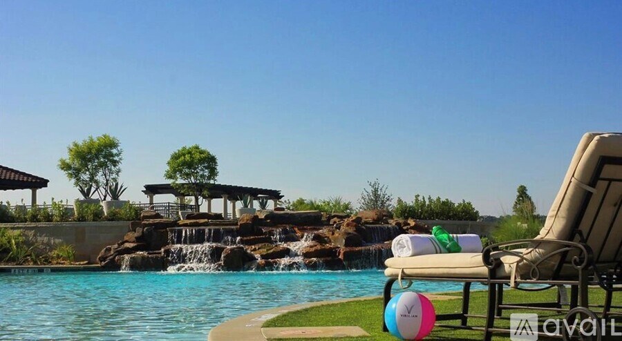 A pool with a waterfall and a lounge chair with a pillow on it.