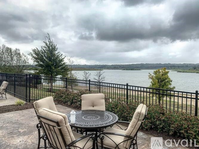 A patio with a table and chairs overlooking a body of water.