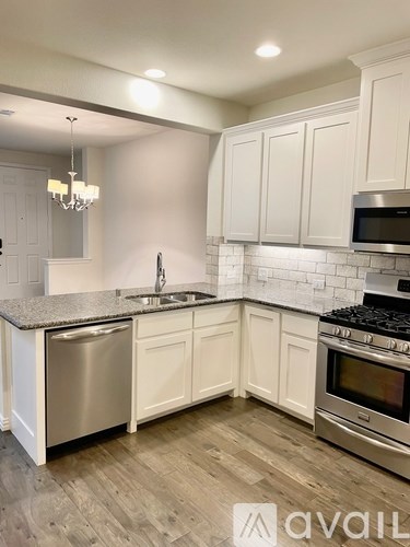 A kitchen with white cabinets and a wooden floor.