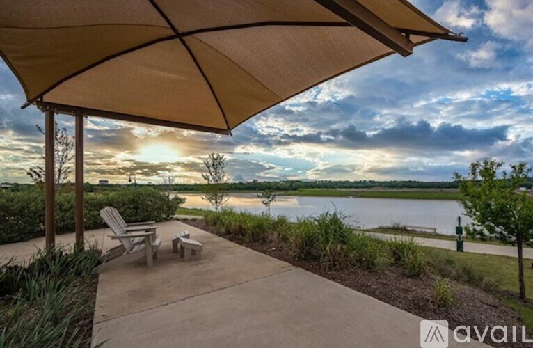 A patio with a table and chairs under a canopy overlooking a body of water.
