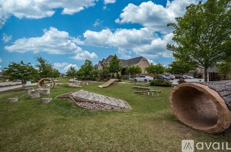 A park with a large wooden sculpture in the foreground and a building in the background.