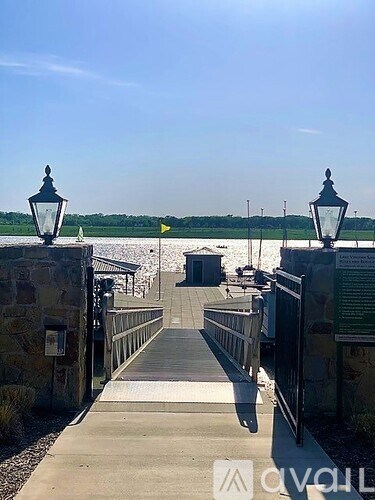 A bridge with lamp posts on either side leading to a body of water.