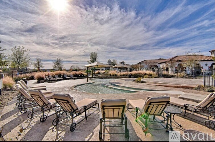 A sunny day at the pool with chairs and a hot tub.