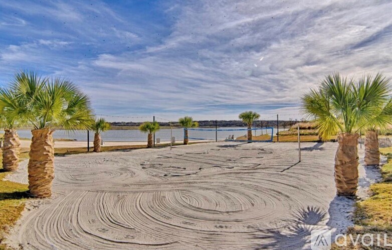 A parking lot with palm trees and a body of water in the distance.
