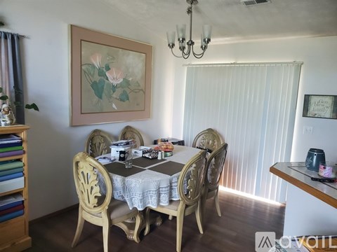 A dining room with a table set for six and a chandelier hanging from the ceiling.
