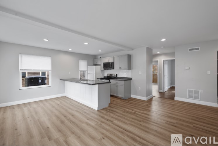 A modern kitchen with wooden floors and white cabinetry is available for rent.