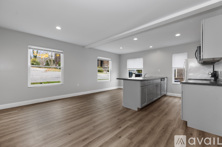 A spacious kitchen with wooden flooring and white cabinets.