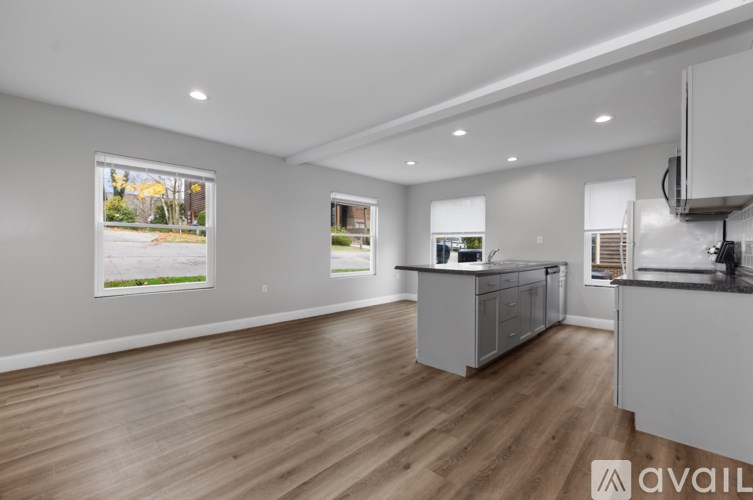 A spacious kitchen with wooden flooring and white cabinets.