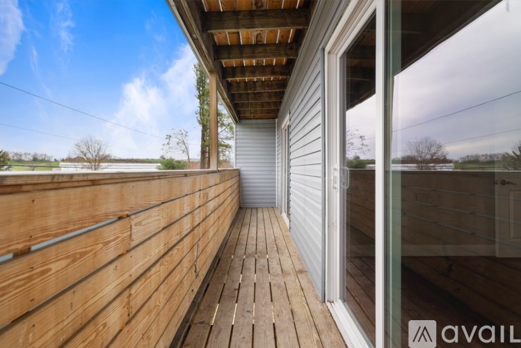A wooden deck with a sliding glass door leading to a patio.