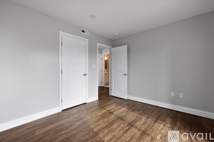 A room with a white door and a wooden floor.