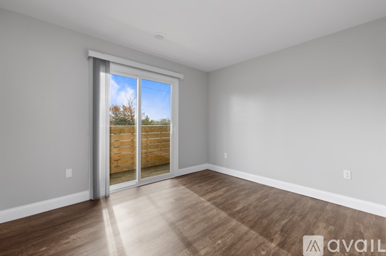 A room with wooden flooring and a sliding glass door leading to a backyard.