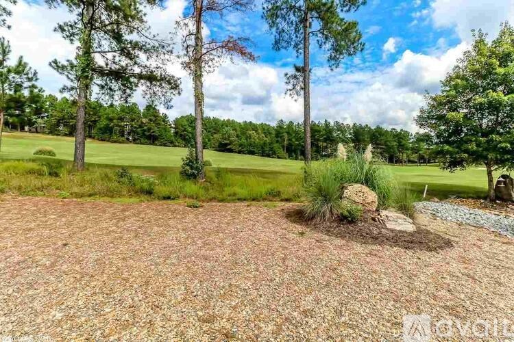 A garden with a brick pathway and a large tree in the background.