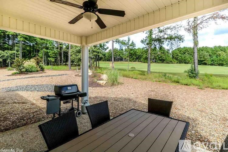 A covered patio with a table and chairs and a grill.