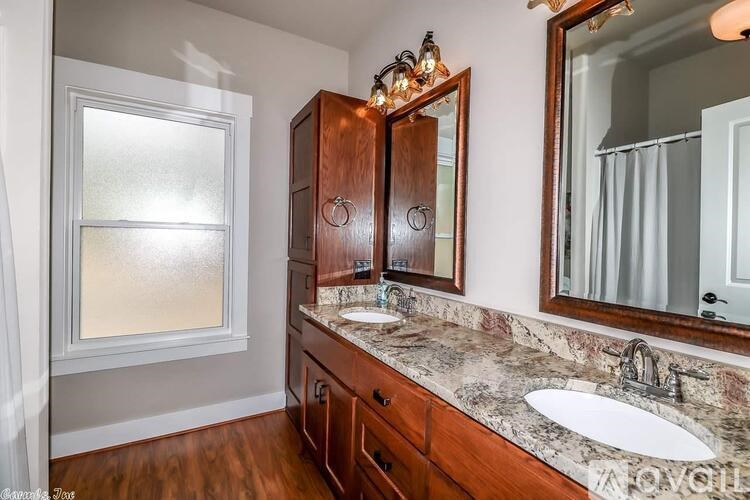 A bathroom with a marble countertop and wooden cabinets.