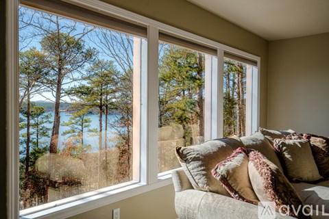 A living room with a couch and a window overlooking a forest.