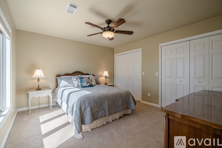 A bedroom with a bed, two lamps, and a ceiling fan.