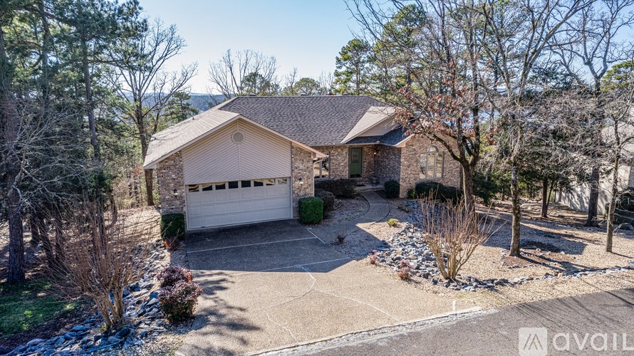 A house with a garage is surrounded by trees and bushes.
