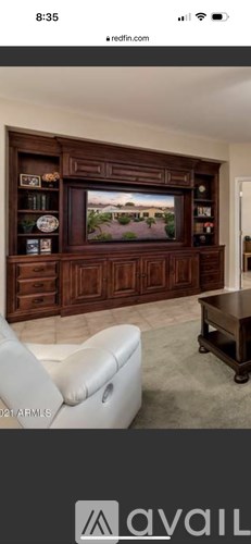 A living room with a large entertainment center and a white leather chair.