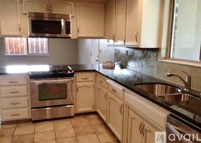 A kitchen with white cabinets and a black countertop.