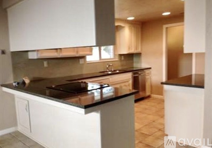 A kitchen with white cabinets and a black countertop.