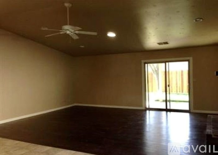 A room with a ceiling fan and sliding glass doors.