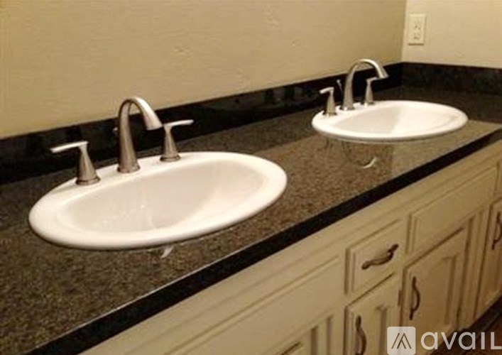 Two white sinks with chrome faucets on a granite countertop.