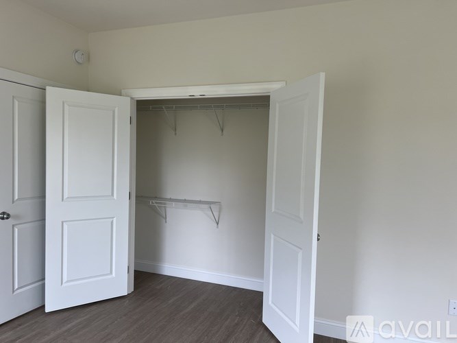 A room with a white door and a white closet with a coat rack.