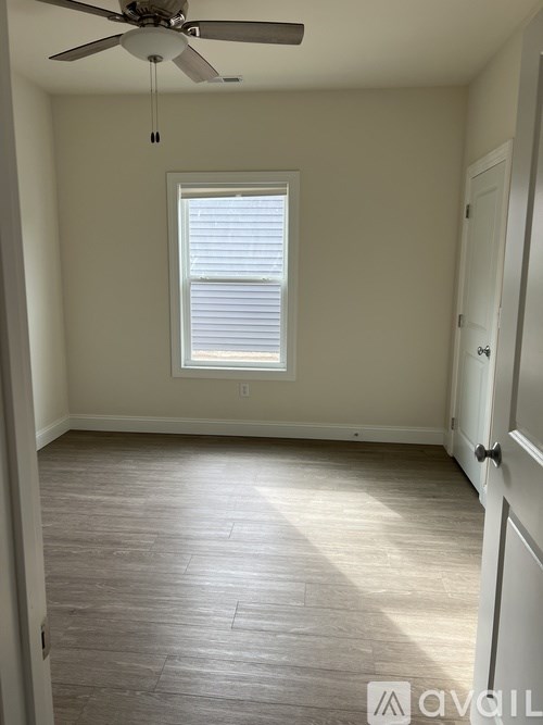 A room with a ceiling fan and a window with blinds.