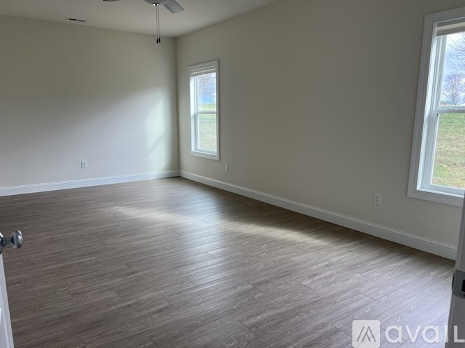 A room with a ceiling fan and two windows.