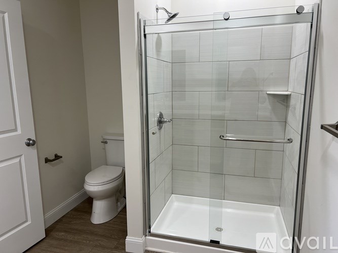 A white toilet sits next to a walk-in shower with a glass door.
