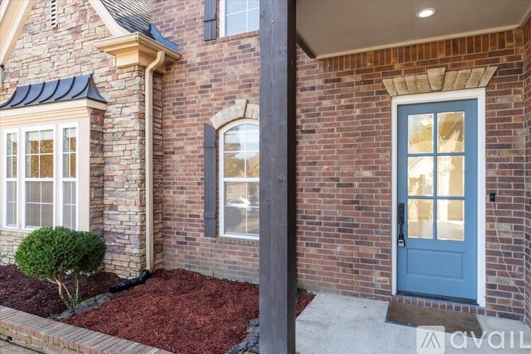 A house with a blue door and a small tree in front.