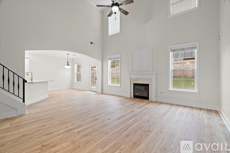 A spacious living room with a fireplace and a ceiling fan.