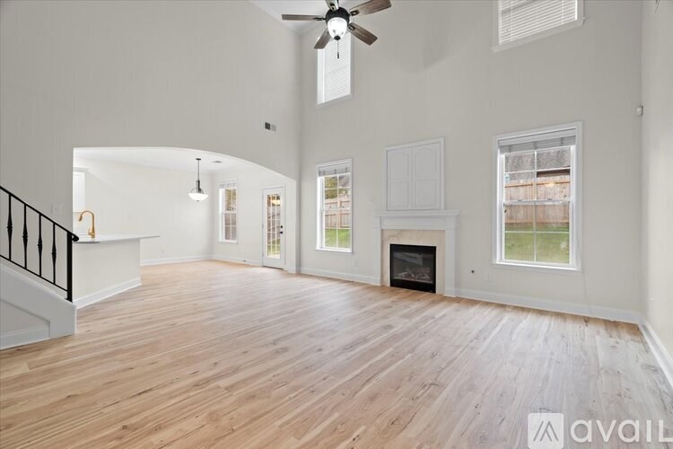 A spacious living room with a fireplace and a ceiling fan.