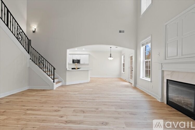 A spacious living room with a fireplace and a staircase with a black railing.
