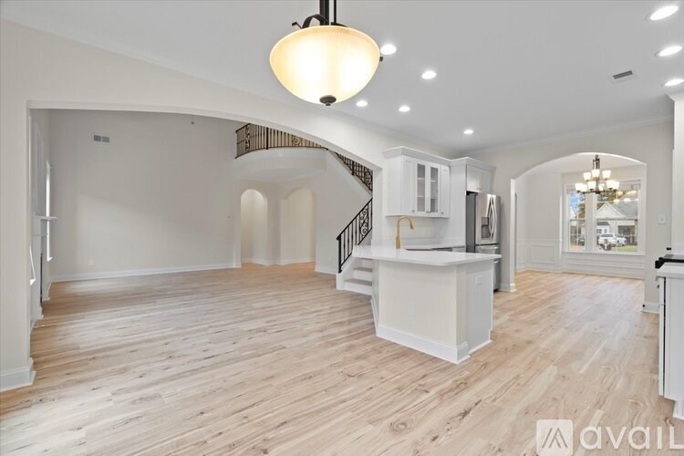 A spacious living room with a staircase and a kitchen area.