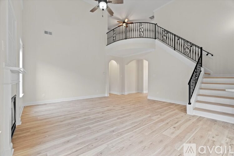 A spacious room with a staircase and a fireplace.