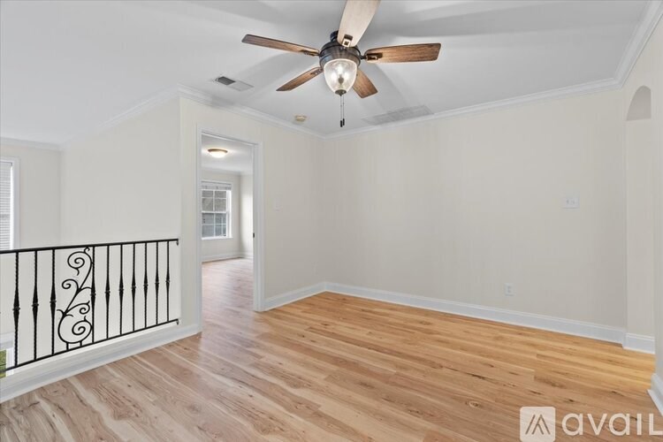 A room with a ceiling fan and wooden flooring.