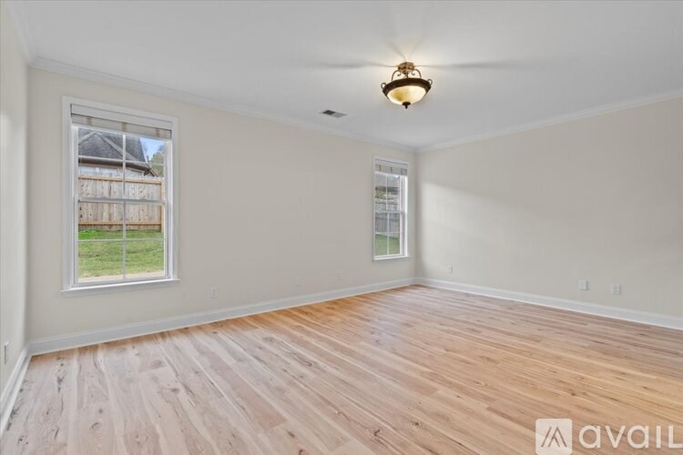 A room with wooden flooring and a window overlooking a fence.