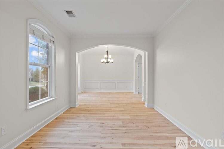 A long hallway with a chandelier and a window.