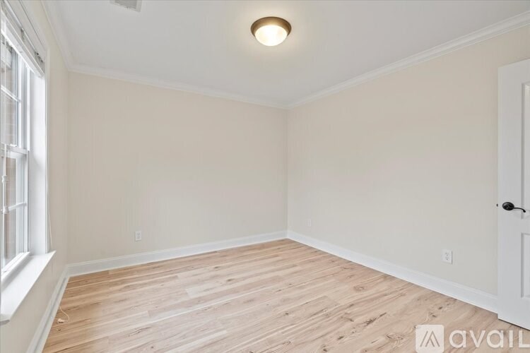 A room with wooden flooring and a window on the left side.