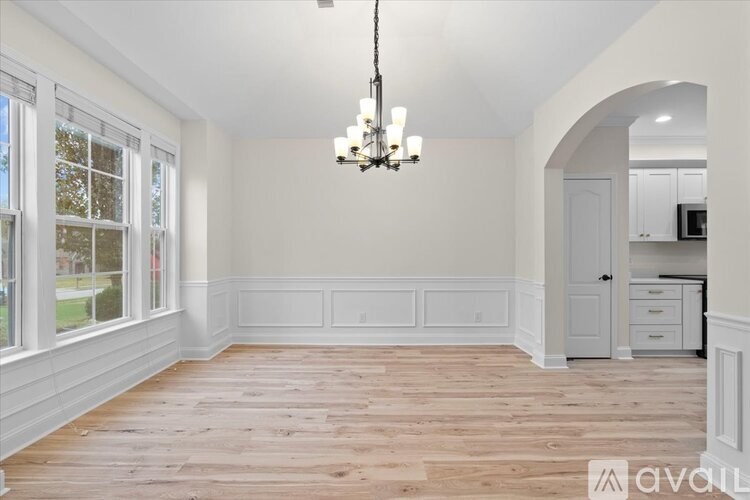 A spacious room with wooden floors and a chandelier hanging from the ceiling.
