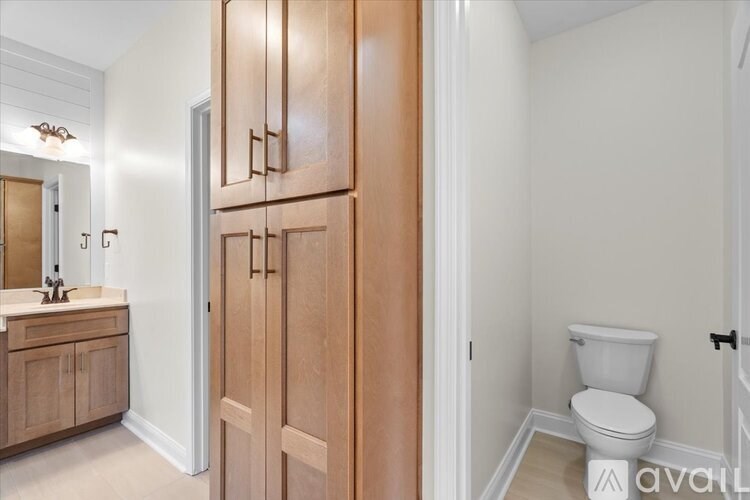 A bathroom with a toilet, sink, and wooden cabinets.