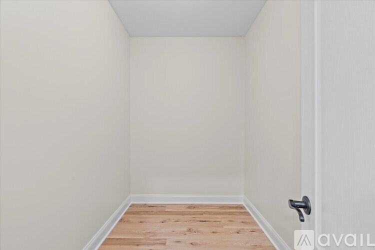 A room with a wooden floor and a door with a black handle.