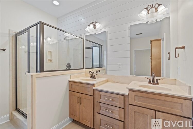 A bathroom with a walk-in shower, double sinks, and wooden cabinets.