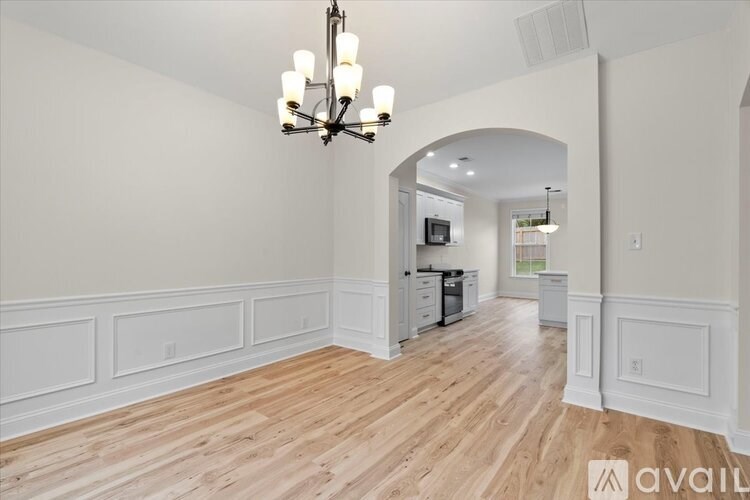 A well-lit room with wooden floors and a chandelier.